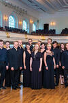 Photo of Yale Choral Artists standing on stage with audience seating behind them